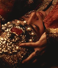 a woman laying on top of a bed covered in jewelry