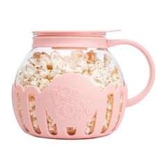 a pink cup filled with popcorn on top of a table