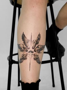 a person sitting in a chair with a tattoo on their leg that has birds flying over them