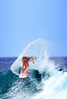 a woman riding a wave on top of a surfboard