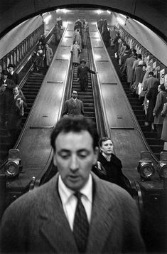 black and white photograph of people on an escalator in a subway or train station