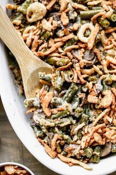 a white bowl filled with green bean casserole and a wooden spoon in it