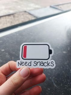 someone holding up a sticker that says need snacks