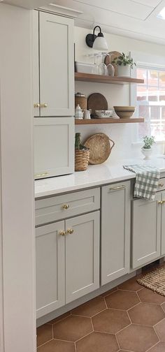 a kitchen with white cabinets and brown tile flooring