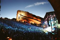 a large group of people standing in front of a mountain at night with bright lights