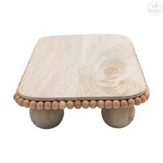 a small wooden table with beads on the legs and a wood top that has been turned into an ottoman