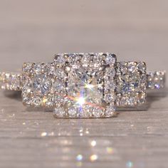 an engagement ring with three rows of diamonds on top of it, sitting on a wooden surface