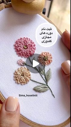 someone is stitching flowers on a piece of fabric