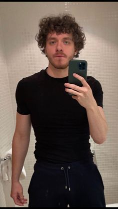 a man taking a selfie in front of a bathroom mirror with his cell phone