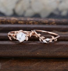 a rose cut diamond ring on top of a wooden surface with leaves and stones in the background