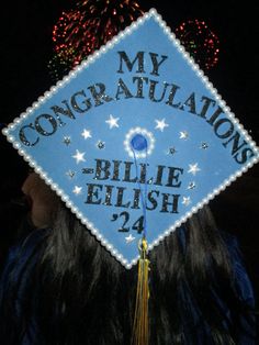 a blue graduation cap with the words my congratulationss written on it and fireworks in the background