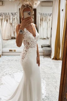 a woman taking a selfie in front of a mirror wearing a white wedding dress