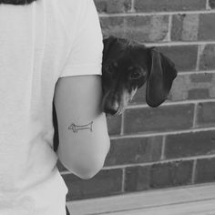 a black and white photo of a dog with a bone tattoo on his left arm