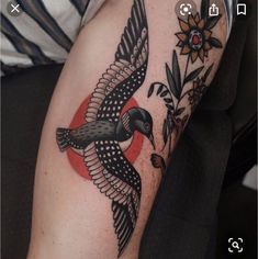 a black and white bird with red circle on it's back half sleeve tattoo