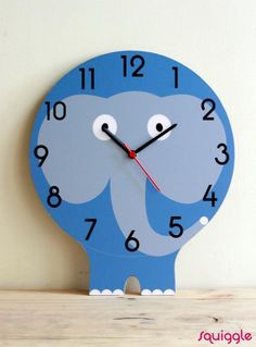 an elephant shaped clock with numbers on the face and hands, sitting on a shelf