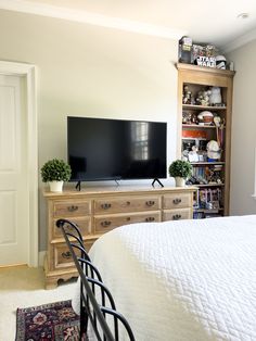 a bedroom with a bed, dresser and television on top of the entertainment center in it