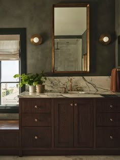 a bathroom with marble counter tops and wooden cabinets, along with a large mirror on the wall