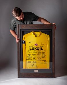 a man holding up a framed shirt in front of his face with the words'lukoi'written on it