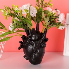 a vase with flowers in it sitting on a table next to a white frame and pink wall