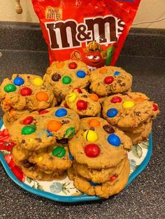 cookies with m & m's candy on top are sitting on a blue plate next to a bag of m & m's