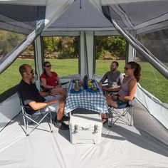 four people sitting at a table in a tent