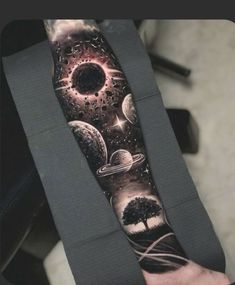 an arm tattoo with planets and trees on it