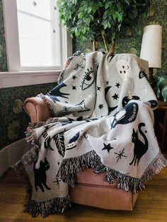 a chair with a blanket on top of it next to a potted plant and window