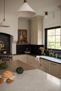 a kitchen with marble counter tops and white cabinets, along with a painting on the wall