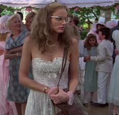 a woman in a white dress standing next to a group of people under a tent