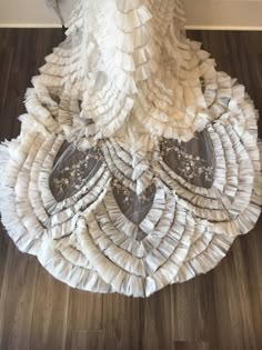 a dress made out of white ruffles on top of a wooden floor next to a door