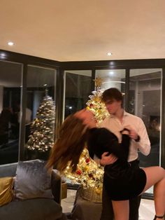 a man and woman dancing in front of a christmas tree