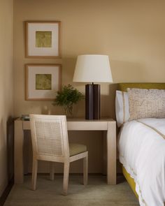 a bedroom with a bed, desk and chair in it's corner next to two framed pictures on the wall