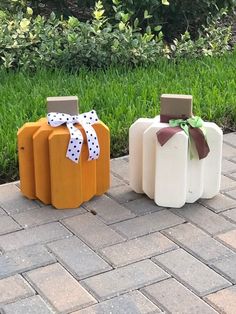 three painted pumpkins sitting on top of a brick walkway in front of green grass