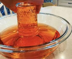 a person pouring liquid into a glass bowl