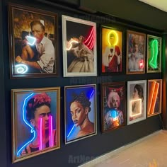 a wall with neon signs and pictures on it's sides, all lit up in different colors