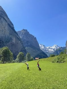 two children are playing in the grass with mountains behind them