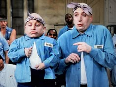 two men in blue shirts with tags on their heads are standing next to each other