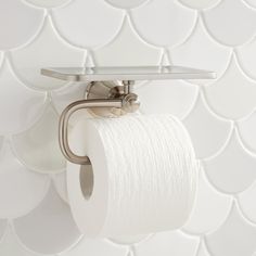 a roll of toilet paper is hanging on the wall next to a metal holder with two rolls of toilet paper in it