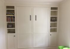 an empty room with white bookcases and green chair in the corner on the floor