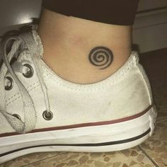 a woman's foot with a small spiral tattoo on the side of her ankle