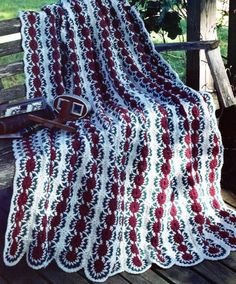 a crocheted blanket sitting on top of a wooden bench