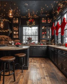 a kitchen decorated for christmas with lights on the ceiling and wooden floors, black cabinets