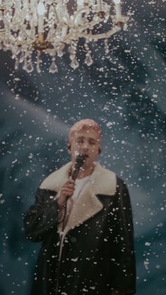 a man standing in front of a chandelier holding a microphone