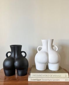 three black and white vases sitting on top of a wooden table