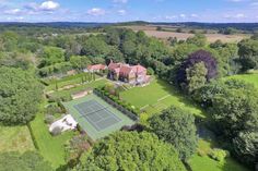 an aerial view of a tennis court in the middle of a lush green field with trees