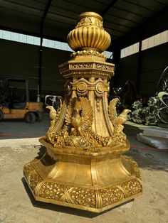 a golden statue is sitting in the middle of a warehouse area with other vehicles behind it