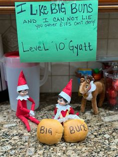 two elfs sitting next to each other in front of a sign that says i like big buns and it can not lie