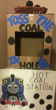 a cardboard box with a train on it and a sign that says toss the coal hole