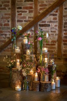 a table topped with lots of candles and vases filled with flowers on top of each other