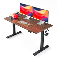 two computer screens sitting on top of a wooden desk